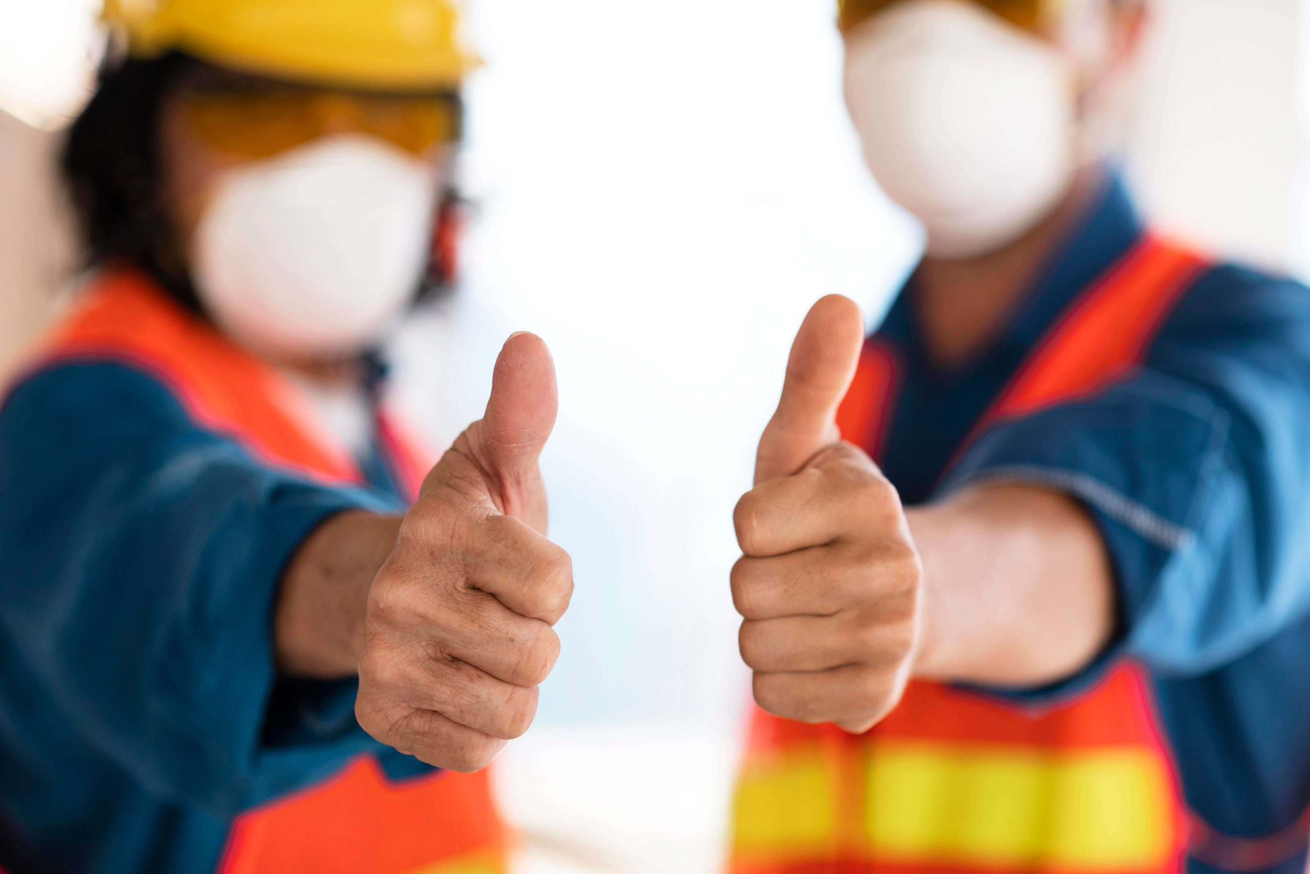 Collega's met veiligheidskleding tonen met hun duim het ok teken